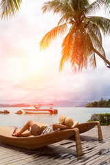 Summer beach vacation concept, Asia woman with hat relaxing and on chair beach with speed boat in back at Koh Payam, Ranong, Thailand