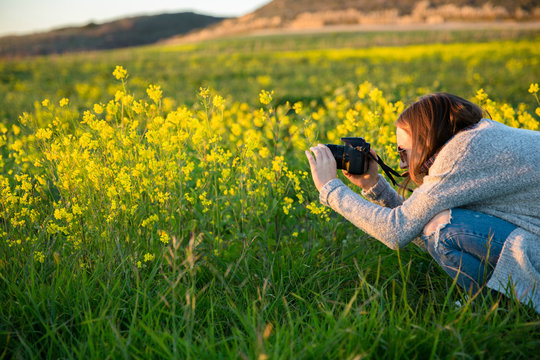 Teenage girl shooting yellow mustard flowers in a field