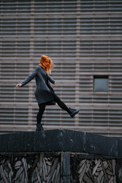 woman playing/dancing in front of a functional architecture building
