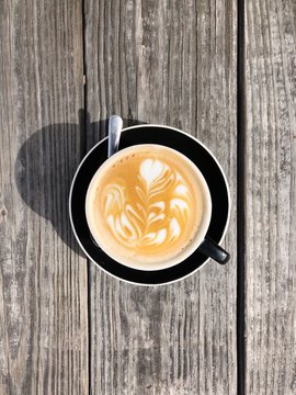 Cappuccino made with espresso coffee and steamed milk with intricate design in foam.