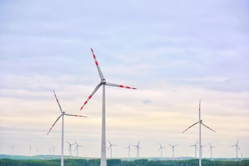 Wind turbines on morning violet sky. Clean electricity. Ecological use natural resources. Wind turbine generating electricity, alternative renewable energy. Rotating blades of wind energy generators. 