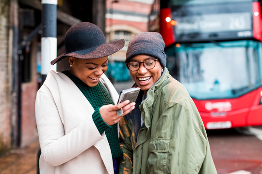 Stylish female friends using mobile phone in London