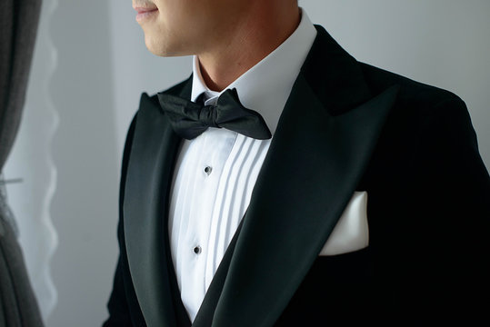 Elegant man wearing black tie suit with white shirt and silk bow tie and white handkerchief or pocket square, sartorial accessories for formal attire, a classy groom or a sophisticated business person