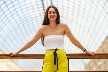 Young beautiful brunette woman in a white top and yellow sports pants