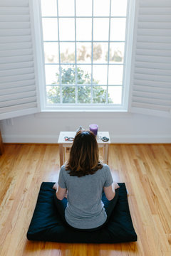 Woman meditating in front of a big window