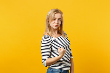 Portrait of successful young woman in striped clothes looking camera doing winner gesture isolated on yellow orange background in studio. People sincere emotions lifestyle concept. Mock up copy space.