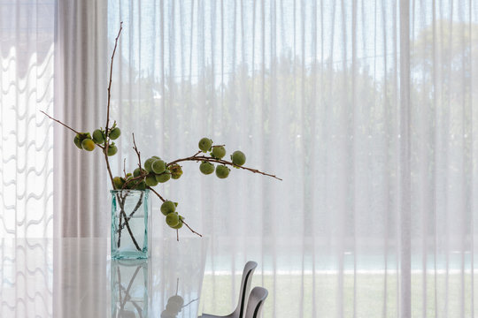 Artistic arrangement of fresh cut persimmon fruit branches in a minimalist kitchen