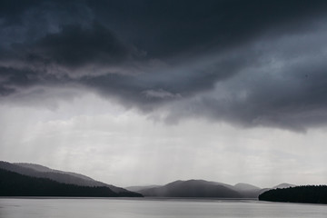 Stormy rain clouds over mountains and a lake