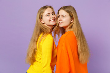 Side view of two attractive young blonde twins sisters girls in