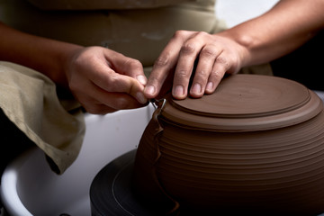 Woman trimming bowl or pot on pottery wheel.