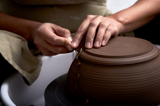 Woman trimming bowl or pot on pottery wheel.