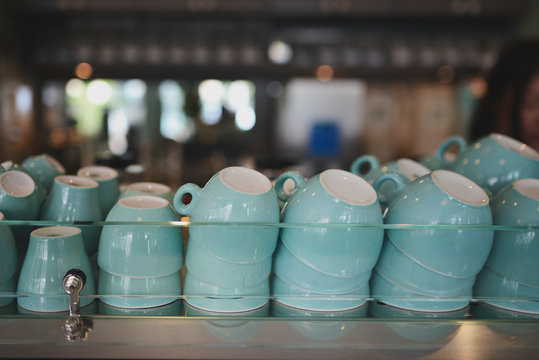 stacks of empty coffee cups on top of an industrial espresso machine in a cafe