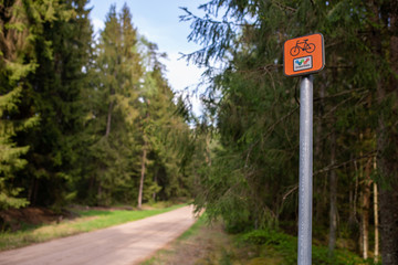 Pomarańczowy znak Green Velo w lesie z widokiem na drogę