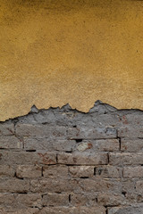 Yellow Painted Concrete Wall Damaged With Bricks Visible
