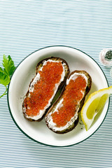 Fresh bread sandwich with red caviar and soft cheese on a plate. classic combination of ingredients. snack on the table