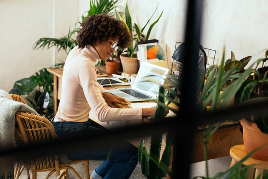 Afro businesswoman working in office full of plants.