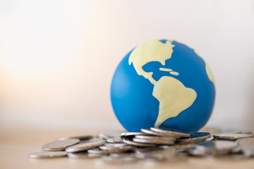 Global Business, Money, Finance and saving concept. Close up of mini world ball on pile of silver...