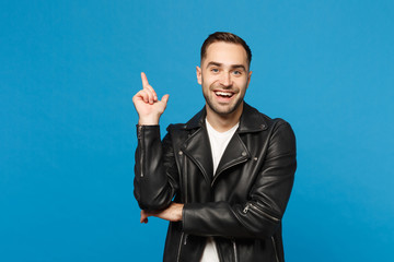 Handsome stylish young unshaven man in black jacket white t-shirt showing on workspace isolated on blue wall background studio portrait. People sincere emotions lifestyle concept. Mock up copy space.