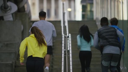 Group of joggers run up some steps before celebrating at the top