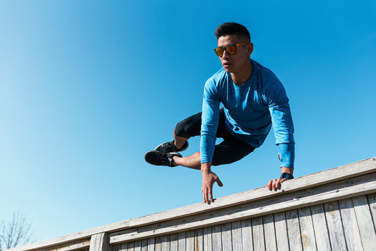 Young asian man practicing parkour in the city.