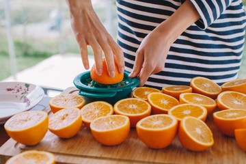 Crop female's hands squeeze orange juice