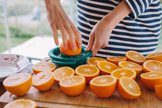 Crop female's hands squeeze orange juice