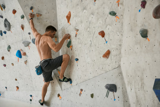 Shirtless sportsman in climbing wall