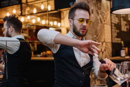 Stylish wine expert open the wine bottle with	corkscrew