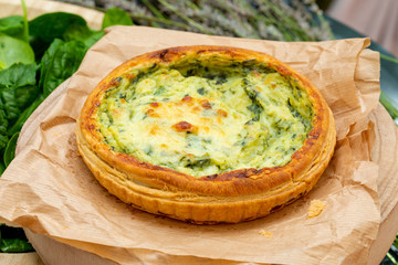 Close-up of quiche with fresh vegetables. Background in green tones. Rustic and country aspect.