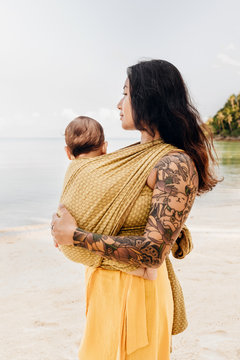 Side view of woman carrying her baby on beach