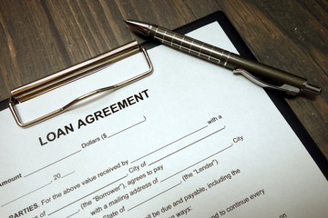 Clipboard with loan agreement and pen on desk