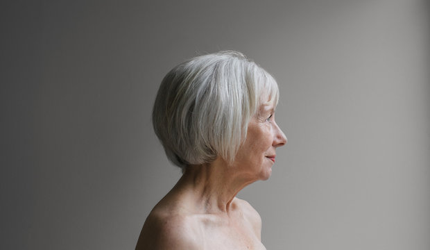 Senior topless woman on simple grey background