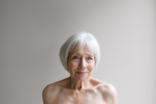 Senior topless woman on simple grey background