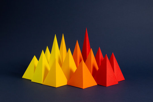 Red, Orange and Yellow paper pyramids on a navy background. (3)