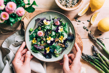 Overhead view of woman's hands holding plate of salad