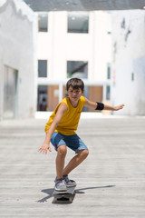 Front view of cheerful skater boy riding on the city in a sunny day