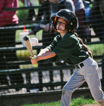 young female ballplayer hits a baseball with the bat