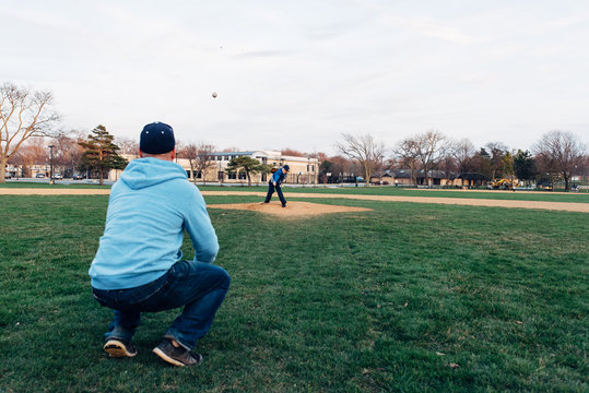 Son throwing a baseball to his Dad on a baseball field