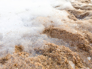 Closeup abstract image of soap foam lying on sandy sea beach after beach disco party