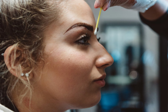 A young woman having her eyebrows micro bladed