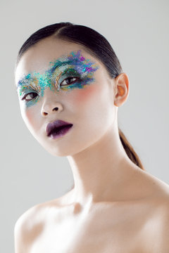 Beautiful model posing in a studio with glitter makeup