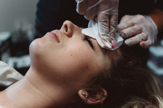 A young woman having her eyebrows micro bladed