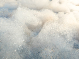 Macro abstract photo of puffy soap foam in bright sun rays against blue sky looking like flying clouds