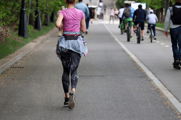 Slim sexy girl running on a road in a summer park. Sporty lifestyle, concept of jogging, workout, active people