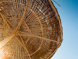 Image of straw umbrellas on the ocean beach at hot sunny day against blue sky