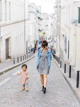Smiling mom and baby walking streets of Paris