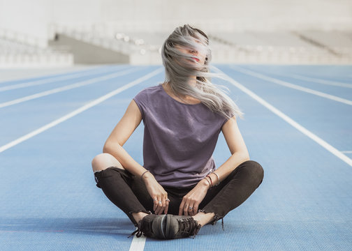 Woman with dyed hair sitting on running track