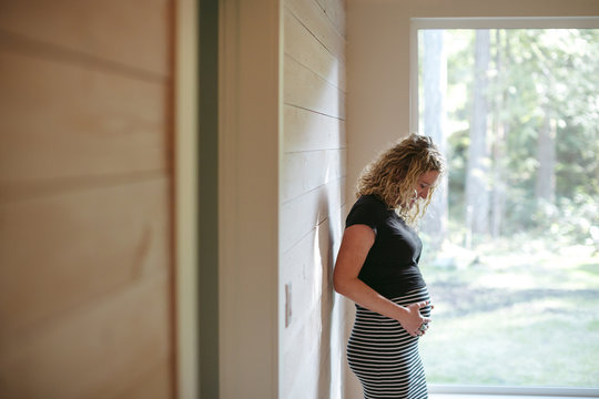 Pregnant woman at home looking at pregnant belly