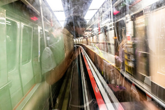The reflection of a young man taking a picture of a moving train in a tunnel.
