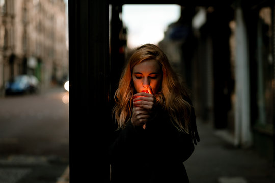 blonde woman lighting on a cigarette on a bus station